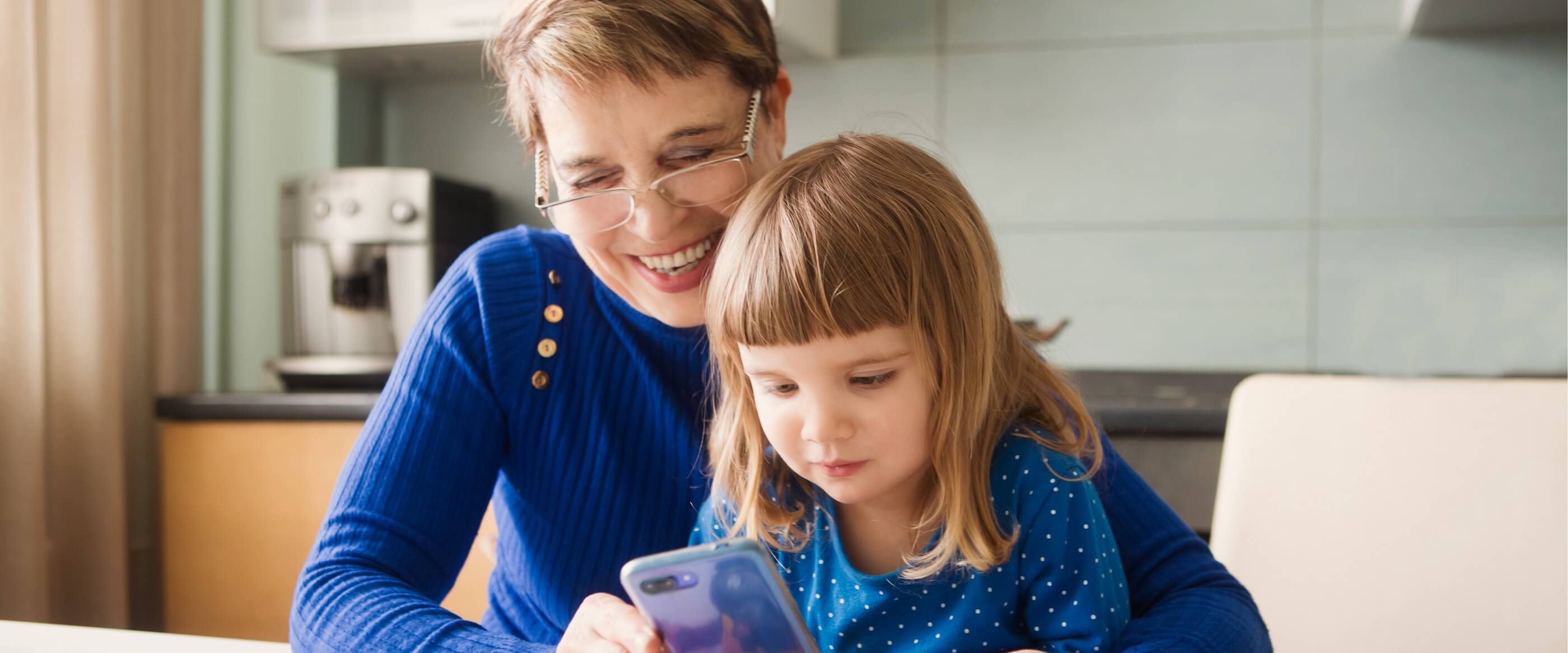 Une grand-mère tenant un téléphone portable avec sa petite-fille.